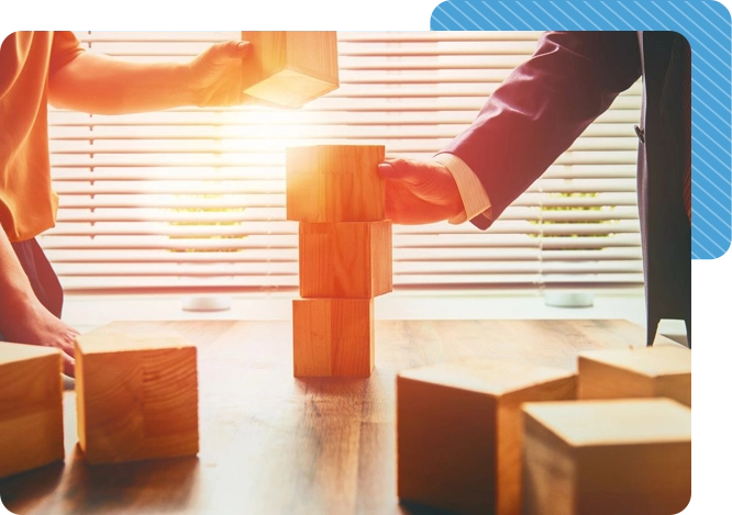 Two people stacking blocks on top of a table.